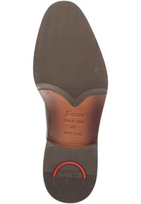 Suola di scarpa in pelle con superficie in gomma marrone texturizzata, design curvato e accentuazione circolare rossa vicino al tallone. Branding "Sioux" visibile.