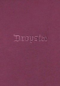 Logo Dropsize brodé en police gothique sur un fond en tissu violet foncé uni.