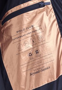 Etykieta odzieży wierzchniej Polo Club na błyszczącym materiale z ikonami przedstawiającymi ultralekkość, dopasowany krój, dodatkowe ocieplenie, wodoodporność, poliester z recyklingu oraz cechy umożliwiające pranie.