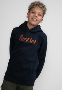 Marineblauwe hoodie gemaakt van zachte stof, met een kangoeroezak en oranje tekst "Petrol Ind" op de voorkant.