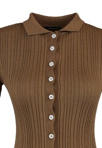 Brun ribbad polo-tröja med korta ärmar, med knappstängning fram och vita knappar, som visar en strukturerad tygdesign.