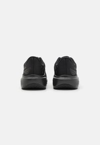 Scarpe sportive nere con tomaia in mesh e colletto imbottito, dotate di una suola in gomma spessa e un motivo di trazione testurizzato.