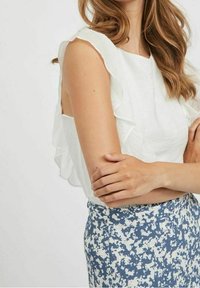 Bílý bezramínkový top s volány, spárovaný s modro-bílou vzorovanou sukní. Texturovaná látka s uvolněným střihem.