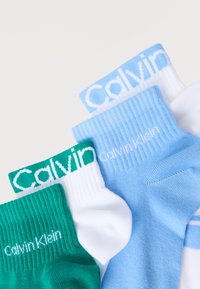 Στοιβαγμένες διπλωμένες κάλτσες Calvin Klein σε πράσινο, λευκό με πράσινη μανσέτα και ανοιχτό μπλε με ορατά λογότυπα στις μανσέτες και τις πλευρές.