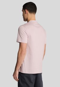 Lyserød t-shirt med korte ærmer og rund hals. Blødt bomuldsstof, minimalistisk design og en lige kant forneden.