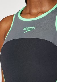 Fato de banho desportivo Speedo com secção superior cinza e sec�ção inferior preta. Apresenta detalhes em verde menta ao redor do decote e no logótipo.