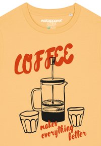 Korte mouwen gele T-shirt met een grafiek van een Franse pers en twee kopjes, met de tekst "KOFFIE maakt alles beter" in het rood.