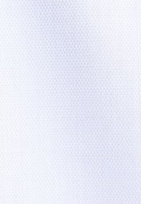 Tissu de chemise blanche avec un motif de texture subtil et un bouton noir près de l'encolure, cousu avec un fil noir.
