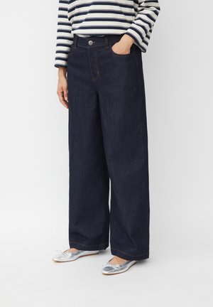 Dark blue wide-leg jeans with a high waist, five pockets, and subtle contrast stitching, paired with silver ballet flats.