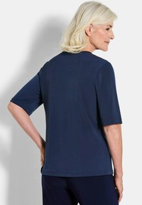 Top blu navy a maniche corte con taglio dritto e texture morbida. Design semplice con scollo tondo e senza pattern o dettagli visibili.
