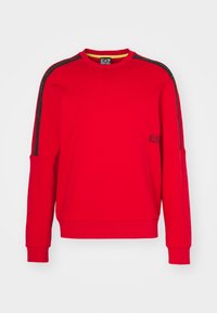 Sudadera roja de manga larga, con rayas laterales negras y un pequeño logo en el pecho. Fabricada en un tejido suave con un cuello redondo.