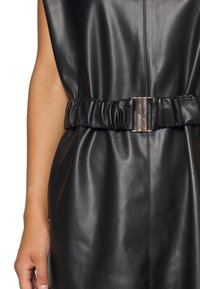 Svart läderklänning med en samlad bälte med metalliska accenter, som visar en slät textur och minimalistisk design.