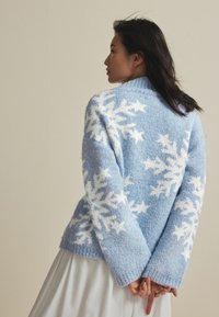 Pullover blu lavorato a maglia con un motivo testurizzato di fiocchi di neve bianchi, dalla vestibilità comoda e con colletto e polsini a coste.
