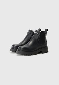 Black leather Chelsea boots with elastic side panels, round toes, and rugged rubber soles. Featuring visible branding at the ankle area.
