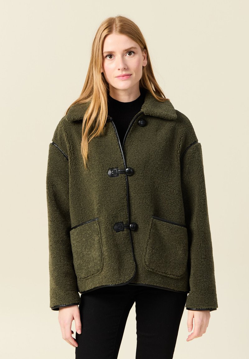 Giacca in fleece verde oliva con rifiniture nere, dotata di colletto, tre bottoni e due tasche anteriori. Texture morbida, design dalla vestibilità ampia.