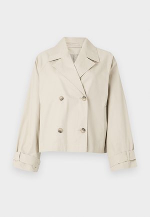 Beige kort jacka med dubbelknäppning, stora slag och knappdetaljer. Har rullade ärmar och en mjuk yta.