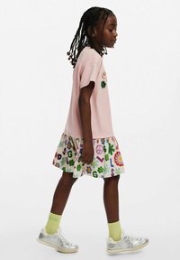 Ljusrosa t-shirtklänning med korta ärmar, som har färgglada blommor i applikationer. Kjolen har en krämfärgad bas med livfulla bokstäver och blommönster.