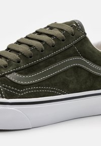 Světlomodré semišové sneakers s bílým prošíváním, texturovanými akcenty a gumovou podrážkou. Obsahuje tradiční šněrovací design a kontrastní černý pruh.