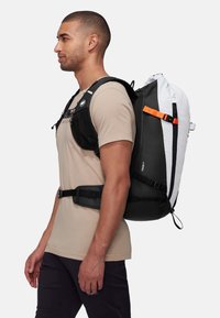 Zwart-witte rugzak met oranje accenten, verstelbare schouderbanden en een zijvak; ontworpen voor gebruik in de buitenlucht. Gestructureerd, duurzaam materiaal.
