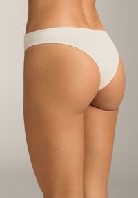 Bež tange glatke teksture i minimalističkog dizajna. Tanka gumica u struku, nisko rezana i bez šavova radi udobnosti i suptilnosti.