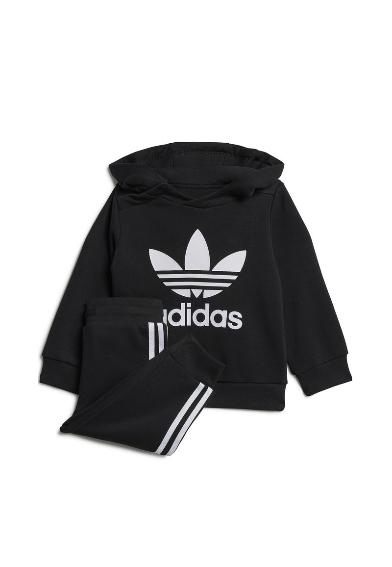 Set sportivo nero composto da una felpa con cappuccio con un grande logo bianco Adidas e pantaloni della tuta abbinati con strisce laterali bianche.