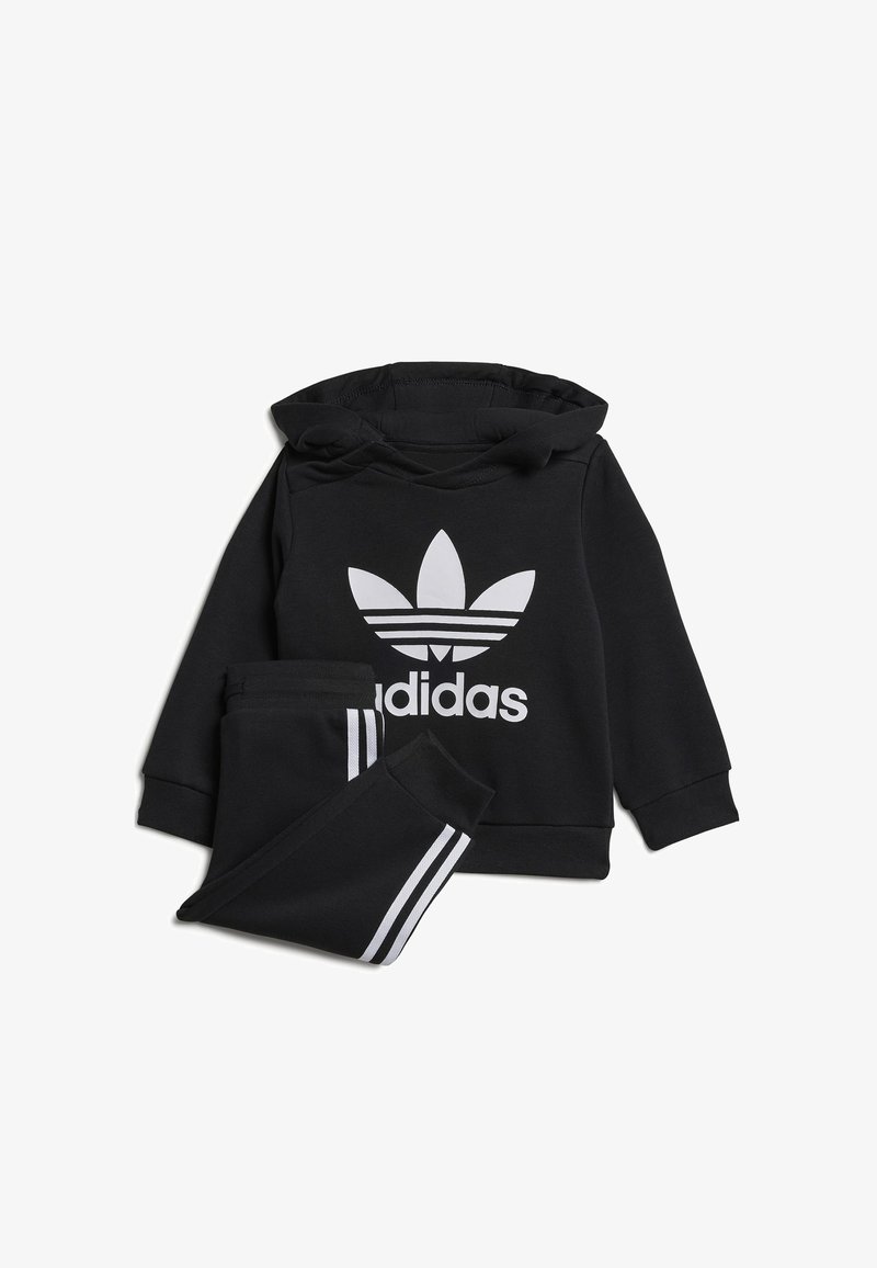 Set sportivo nero composto da una felpa con cappuccio con un grande logo bianco Adidas e pantaloni della tuta abbinati con strisce laterali bianche.
