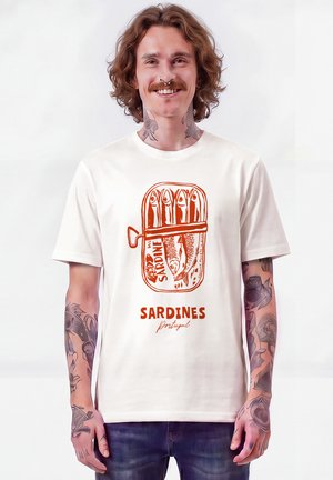 Mann mit Tätowierungen und Septum-Piercing, der ein weißes T-Shirt mit einer orangefarbenen Sardinendosen-Illustration und dem Text "Sardines Portugal" trägt.