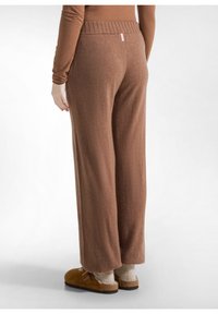 Bruine wijde gebreide broek met een geribbelde tailleband en een zachte textuur, gecombineerd met bruine suède klompen en gebreide sokken.