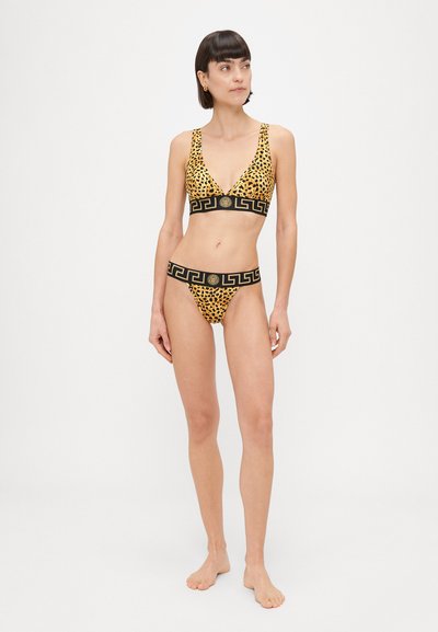 Žltý bikiny s leopardím vzorom a čiernym vzorovaným pásom. Vrchná časť má hlboký výstrih do V, spodná časť má zhodný dizajn na páse.