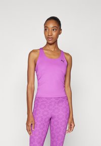 Lilla tanktopp med en fitted design och svart logo, kombinert med matchende mønstrede tights. Glatt stofftekstur.