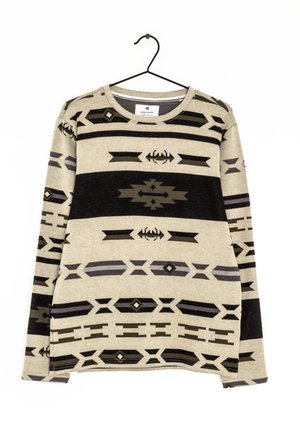 Pull beige à manches longues avec des motifs géométriques et tribaux noirs et gris, suspendu sur un cintre noir contre un fond blanc.