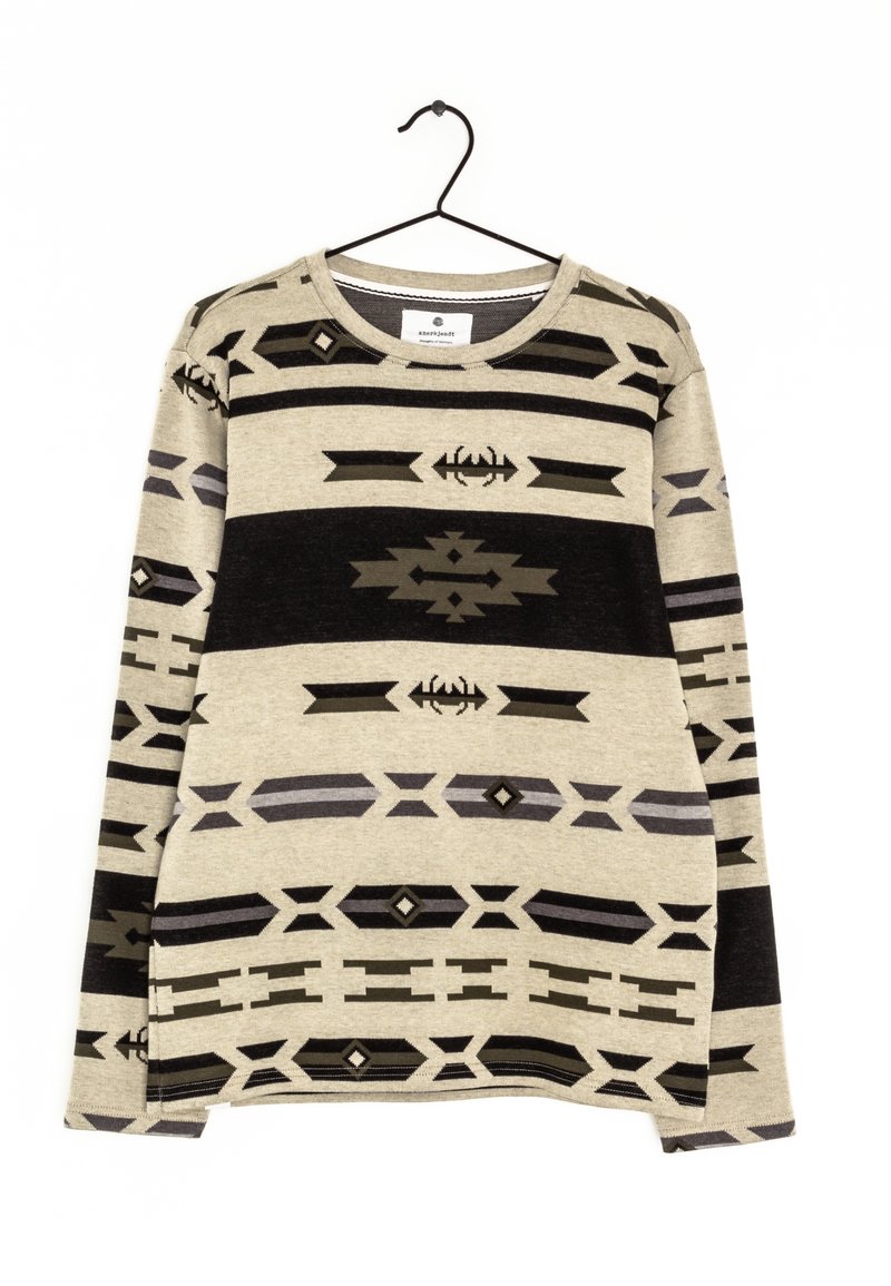 Beige Pullover mit langen Ärmeln und schwarzen sowie grauen geometrischen und tribal Muster, hängt an einem schwarzen Kleiderbügel vor einem weißen Hintergrund.