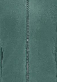 Ciemnozielona polarowa kurtka z zamkiem błyskawicznym z przodu oraz miękkim, teksturowanym materiałem. Prosty design bez dodatkowych wzorów czy ozdób.