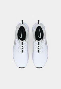 White athletic shoes with a smooth upper, black insoles featuring a silver Nike logo, and a sleek design. Laces are white with silver accents.