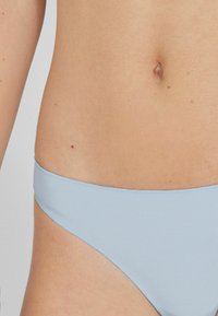 Jasnoniebieskie majtki bikini o gładkiej, miękkiej fakturze. Posiadają niską talię oraz minimalne wycięcia w pasie i nogawkach.