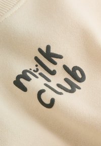 Tela beige con texto negro que dice "mi cltk club" impreso en ella.