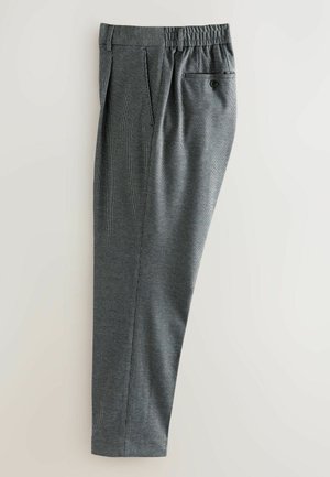 Grijze geruite broeken gepresenteerd tegen een lichte achtergrond, met een elastische tailleband en een achterzak met knoopsluiting.