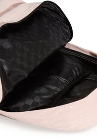 Sac à dos en velours côtelé rose clair avec un intérieur noir présentant un motif à carreaux subtil. Il comprend une fermeture éclair et des accents texturés.