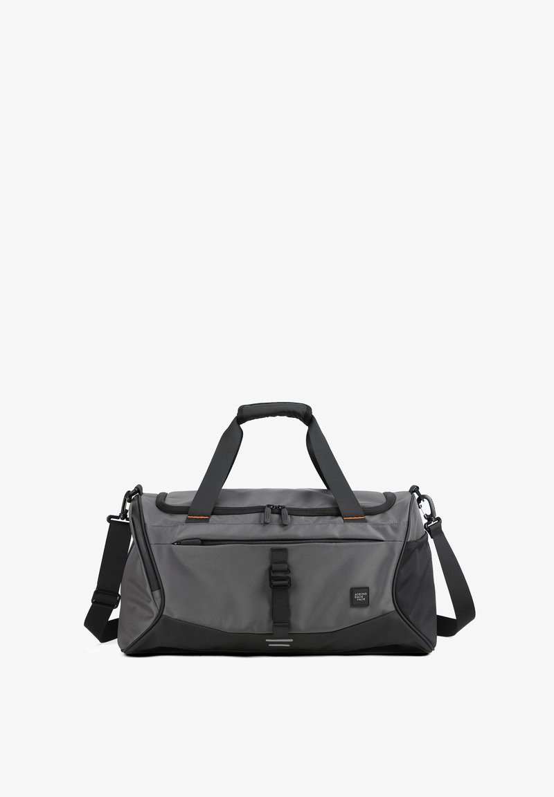 Sac de sport gris et noir avec doubles poignées, bandoulière ajustable, poche avant zippée et fermeture à boucle sur fond uni.