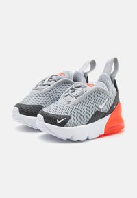 Baskets Nike avec une tige en mesh gris, des accents noirs, des détails orange et une semelle blanche avec une unité de coussin d'air visible.