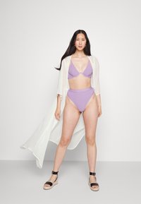 Biquíni roxo texturizado com um fundo de cintura alta a condizer, combinado com um quimono branco translúcido. Sandálias de espadrille pretas completam o visual.