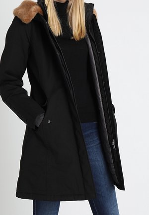 Zwarte lange parka met een capuchon van bont, ritssluiting aan de voorkant en twee zijzakken. Gevoerd met grijze stof, heeft een ontspannen pasvorm en recht ontwerp.