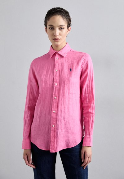 Chemise en lin rose à manches longues, col boutonné et logo brodé sur la poitrine gauche. Tissu texturé et légèrement froissé.