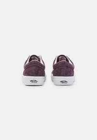 Sneaker in suede viola con suole e accenti in gomma bianca. Presenta un collare imbottito e il logo Vans sul tallone. Design classico con lacci.