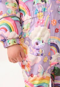 Heller, farbenfroher, lila Pufferjacke mit Cartoon-Tieren, Regenbögen, Blumen und Wolken. Das Material ist glatt und hat elastische Bündchen.