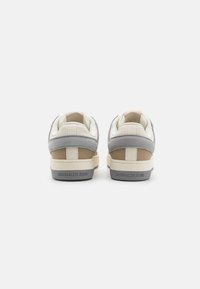 Sneakers Calvin Klein Jeans in pelle beige, crema e grigia. Design low-top con finitura testurizzata e logo sul tallone. Suole in gomma.