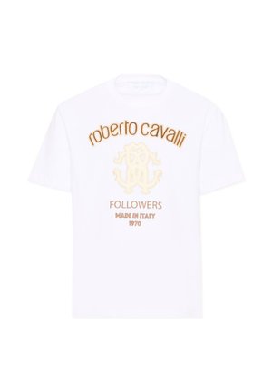 Camiseta blanca con texto marrón "roberto cavalli,", un logo beige y texto más pequeño que dice "FOLLOWERS MADE IN ITALY 1970" en la parte delantera.