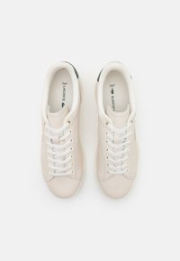 White leather sneakers with a smooth finish, white laces, and a green accent on the heel. Features a cushioned interior for comfort.