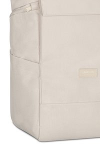 Sac à dos en tissu beige avec poche latérale, fermeture éclair supérieure et une étiquette rectangulaire indiquant "LARKSON HAMBURG" sur le panneau avant.