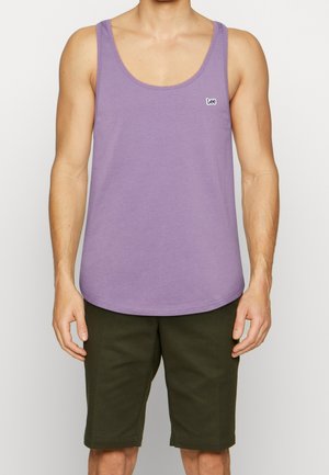 Lila Tanktop aus Baumwolle mit rundem Ausschnitt und kleinem gesticktem Logo. Kombiniert mit dunkelgrünen, knielangen Shorts.